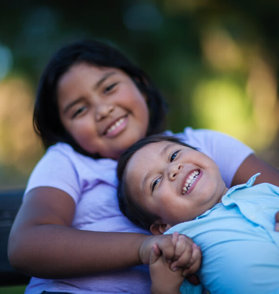 Little brother enjoying the company of his sister as he laughs with a joyful expression and holds her hand.