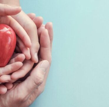 hands holding red heart on aqua background, heart health, donation, CSR concept, world heart day, world health day, family day, wellbeing, hope and gratitude, covid-19, coronavirus relief concept