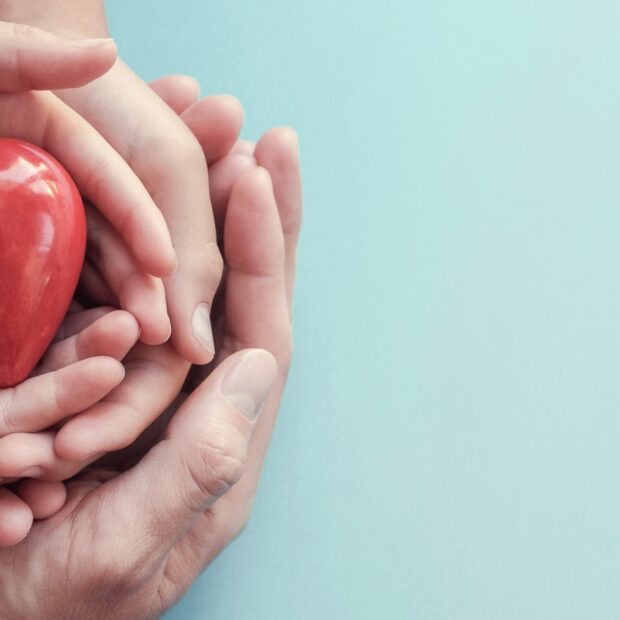 hands holding red heart on aqua background, heart health, donation, CSR concept, world heart day, world health day, family day, wellbeing, hope and gratitude, covid-19, coronavirus relief concept