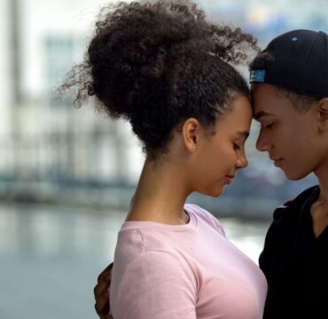 Black couple of teenagers hugging during outdoor date, love connection affection